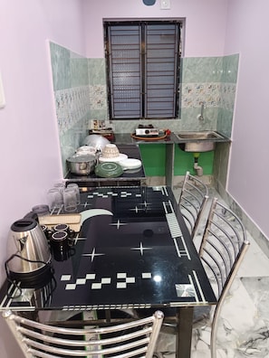 Une cuisine compacte comprenant une table à manger, des chaises, un évier et divers ustensiles de cuisine.