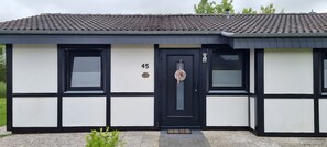 Een gebouw met een zwart-wit gevel, een zwarte deur met het nummer '45' erboven, en een klein kerstkransje aan de deur.