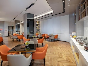 A modern hotel lobby with a central seating area, a reception desk, and a kitchen area. - Echarm Hotel (Heyuan)
