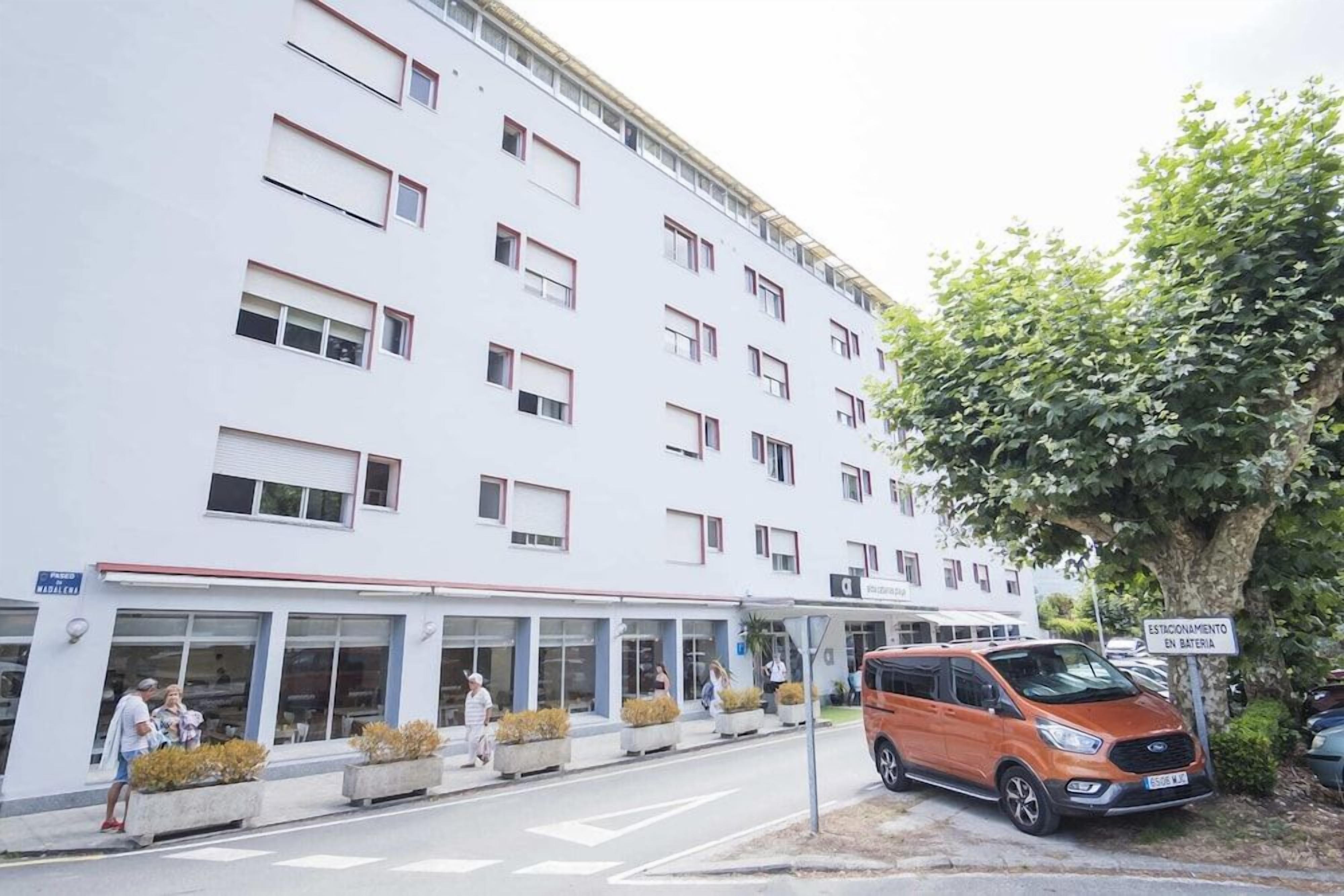 Ein mehrstöckiges Gebäude mit einer überdachten Passage und einem Parkplatz.