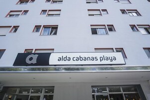 Un edificio con un letrero que dice 'alda cabañas playa' y varias ventanas.