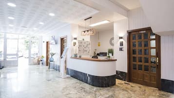 Un espace d’accueil doté d’un comptoir en marbre, d’une porte en bois et d’un plafond orné de motifs.