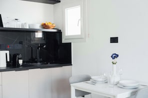 A modern kitchen with a black countertop, white cabinets, and a window above the sink. - Modern Central Studio Walk to Beach & Dining (Lemesos)