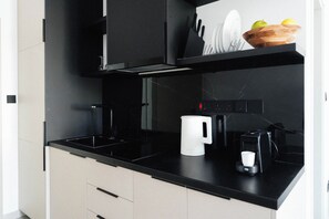 A modern kitchen with a black countertop, a coffee maker, and a kettle. - Modern Central Studio Walk to Beach & Dining (Lemesos)