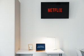 A white desk with a laptop, a framed book, and a wall-mounted sign that reads 'NETFLIX'. - Modern Central Studio Walk to Beach & Dining (Lemesos)