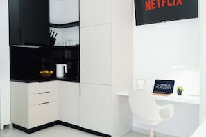 A modern kitchen with a black microwave, white cabinets, and a fruit bowl. There is a white desk with a laptop and a sign that reads 'CYPRUS HORIZONS'. - Modern Central Studio Walk to Beach & Dining (Lemesos)