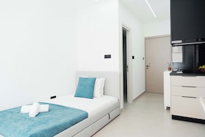 A modern bedroom with a bed, a bedside table, a wardrobe, and a door leading to another room. - Modern Central Studio Walk to Beach & Dining (Lemesos)