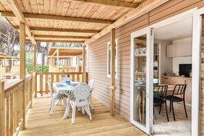 Una terrassa coberta a l'aire lliure amb taula i caires, i una porta corredissa de vidre que dona a una zona de cuina.