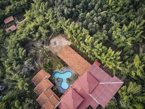 Vista aèria d'una propietat amb diversos edificis, una piscina i vegetació abundant a la rodalia.