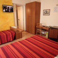 Una camera da letto con due letti, una scrivania, una sedia, un armadio e un televisore.