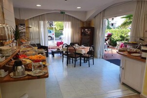 Un'area ristorazione di un hotel con un buffet, un tavolo con sedie e vista sull'esterno.