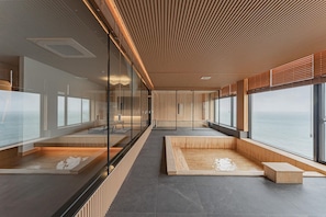 A modern interior with a view of the sea, wooden flooring, and glass partitions. - Denbasta Ryokan Hotel (Geoje)