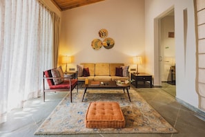 A living room with a sofa, armchairs, a coffee table, and a patterned rug. - Brij Bageecha (Amer)