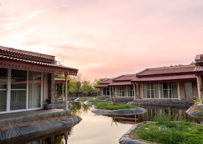 A traditional building with a tiled roof, a courtyard with a water feature, and a garden area with plants. - Brij Bageecha (Amer)