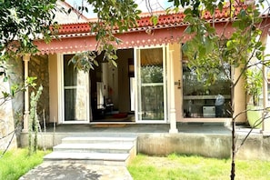 A building with a red tiled roof, large glass doors, and a stone facade. - Brij Bageecha (Amer)