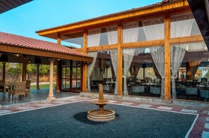 Un edificio con amplios ventanales, un patio techado y una fuente central.