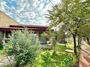 Un patio con un edificio de piedra, un sendero y varios arbustos.