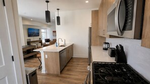 A modern kitchen with a central island, stainless steel appliances, and a microwave above the stove. - The James Suite Two | New 2BR Beach Block (Atlantic City)