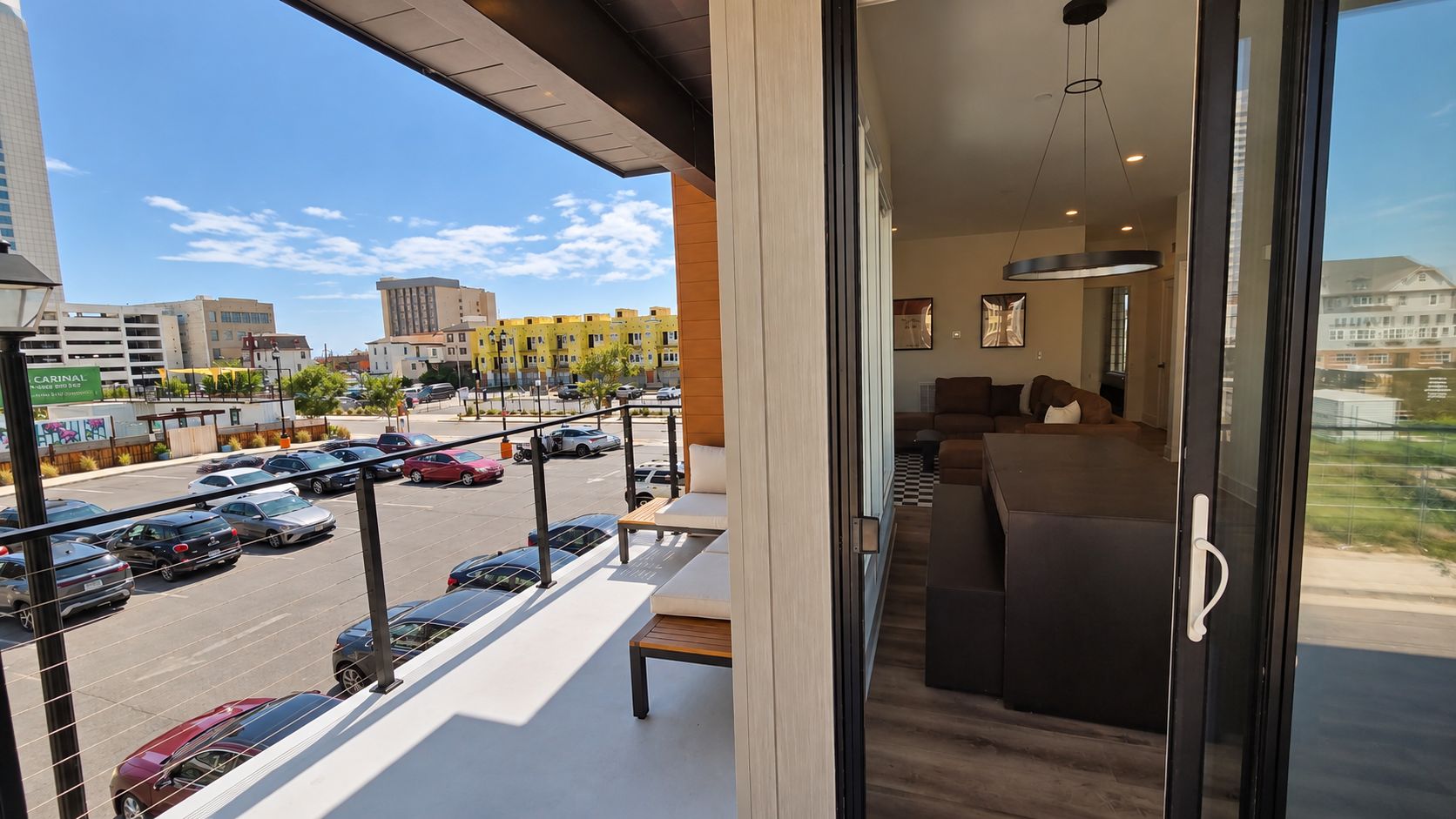 A balcony with a view of a parking lot and buildings.