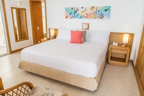 Una habitación de hotel con una cama grande, dos mesitas de noche con lámparas, un cuadro colgado en la pared y una puerta de madera.