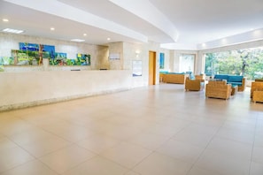 A spacious lobby with a reception desk, wicker furniture, and large windows. - Irotama Resort Zona Torres (Santa Marta)
