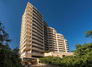 Un hotel de varios pisos con una fachada curva, balcones en cada planta y una entrada central.