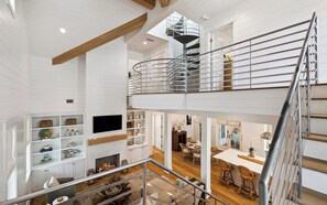 Ein mehrgeschossiges Interieur mit einer Wendeltreppe, offenen Regalen, einem Kamin und einem Essbereich.