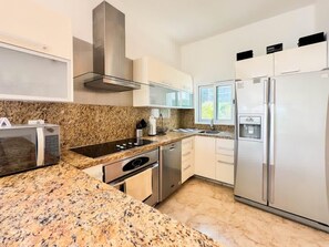 A modern kitchen with granite countertops, stainless steel appliances, and a window providing natural light. - New Listing! Beachfront 2BR with Ocean View, Pool & Parking (Playa del Carmen)