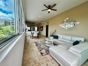 A modern living room with a sofa, coffee table, and a dining area with chairs. - New Listing! Beachfront 2BR with Ocean View, Pool & Parking (Playa del Carmen)