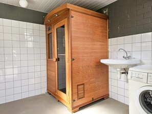 A compact bathroom with a wooden cabinet, a sink, and a washing machine. - Ok40 Chalet Oostkapelle (Oostkapelle)