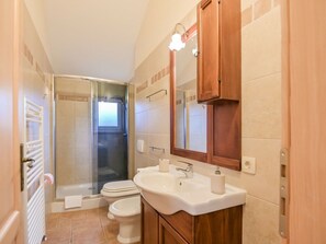 A bathroom with a glass-enclosed shower, a white sink, and a wooden cabinet. - Villa in Kras, Dobrinj With Swimming Pool (Dobrinj)