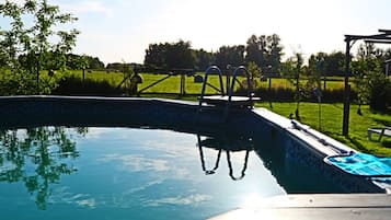 Une piscine avec un plongeoir et une zone herbeuse en arrière-plan.