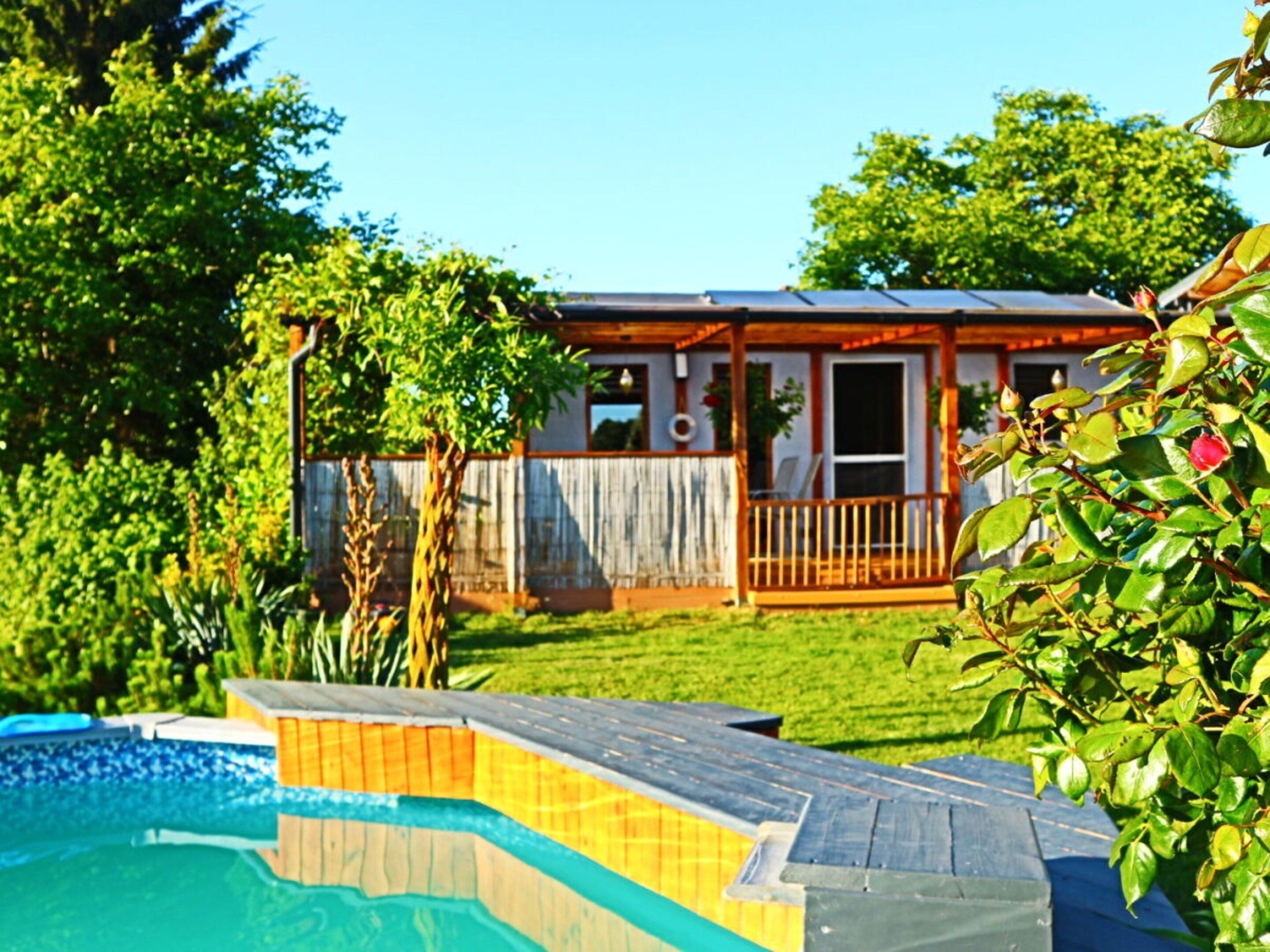 Une propriété résidentielle dotée d’une piscine, d’une terrasse en bois et d’un jardin clôturé.
