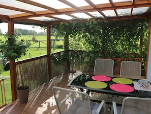 An outdoor patio with a table and chairs, surrounded by a wooden pergola and a view of a green field. - Spa'nsea Bungalow (Stepnica)
