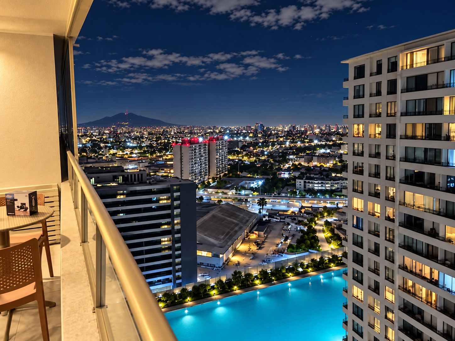Un hotel moderno de gran altura con piscina, que ofrece vistas de un paisaje urbano nocturno.