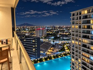 A high-rise hotel with a pool, offering views of a cityscape at night.