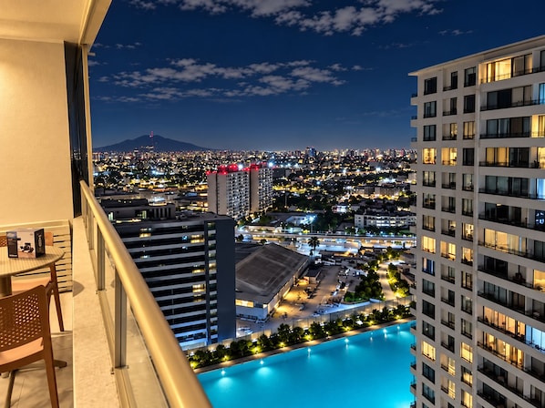 A high-rise hotel with a pool, offering views of a cityscape at night.