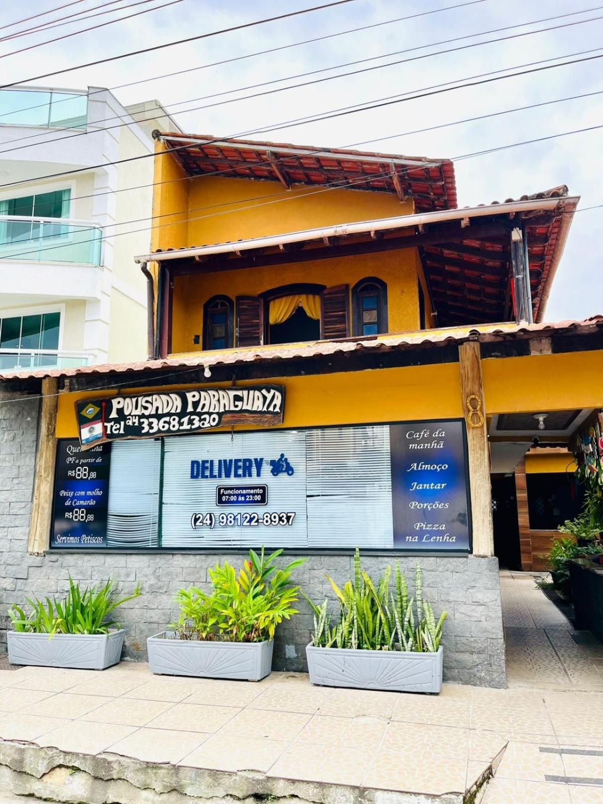 Un edificio con un letrero de servicio de entrega, un número de contacto y un menú que ofrece café, desayuno y pizza.