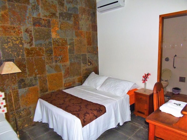 A bedroom with a bed, a nightstand, a chair, and a bathroom door. - Pousada Paraguaya (Angra dos Reis)