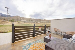 Eine Terrasse im Freien mit Holzzaun, Korbmöbeln und einem dekorativen Teppich.