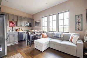 A modern kitchen with stainless steel appliances, a dining area with a table and chairs, and a large window providing natural light. - The Wheelhouse – Private 1BR near Garden of the Gods & Old Colorado City (Colorado Springs)