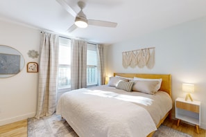 A bedroom with a bed, a nightstand, a ceiling fan, and a window with curtains. - Pickleball, Hot tub, beach access, (OBreeze) (Westport)