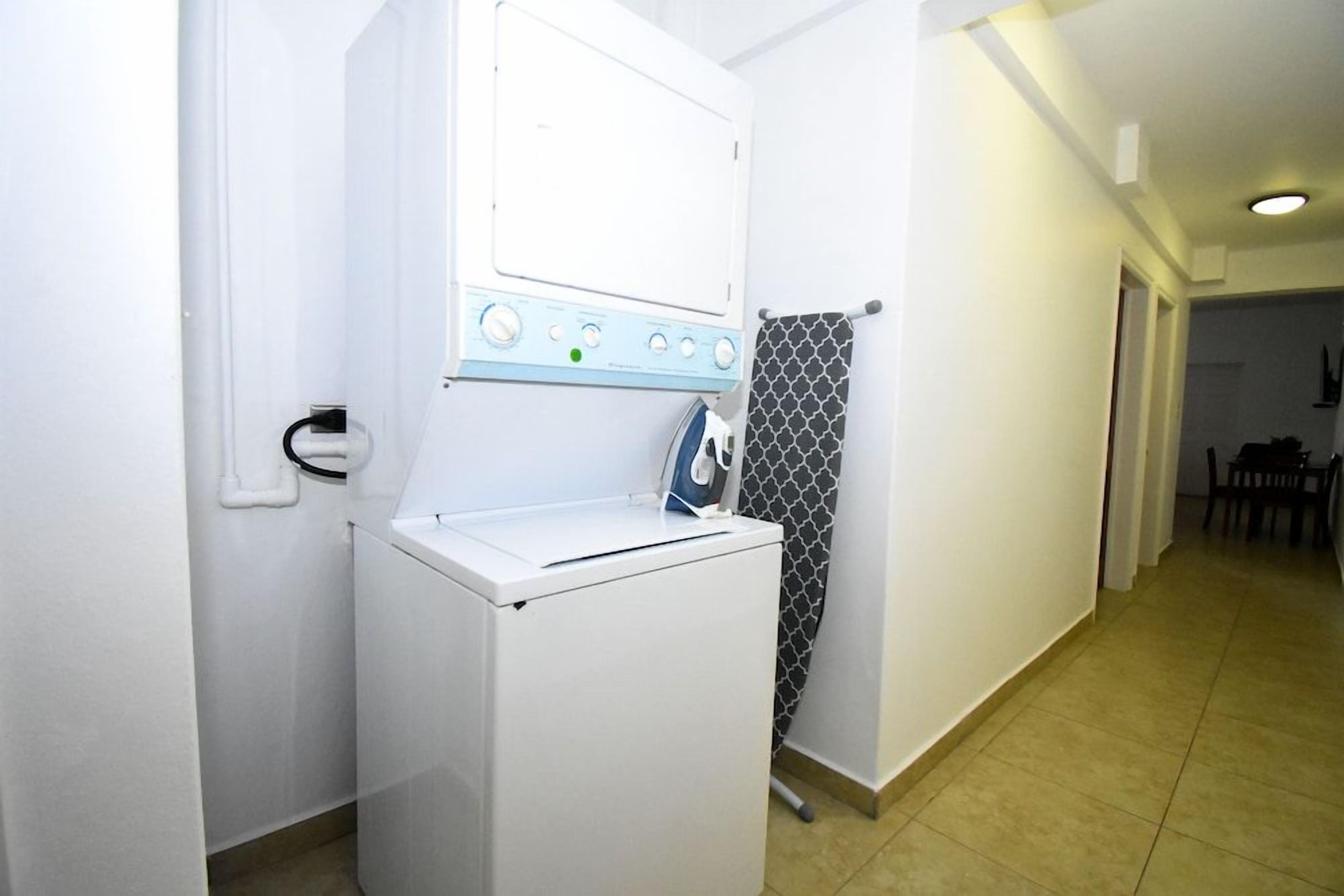 A compact laundry area with a washing machine and dryer, a towel rack, and a patterned shower curtain.