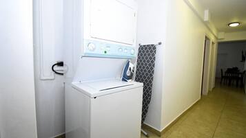 A compact laundry area with a washing machine and dryer, a towel rack, and a patterned shower curtain.