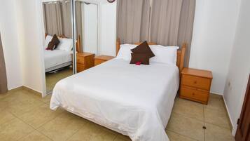 A hotel room with a bed, wooden nightstands, a mirror, and a sliding door.