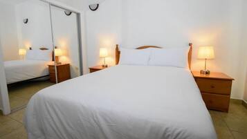 A hotel room with a single bed, two bedside tables with lamps, a mirror, and a sliding door.