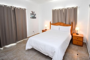 Un dormitorio con una cama individual, dos mesitas de noche y cortinas.