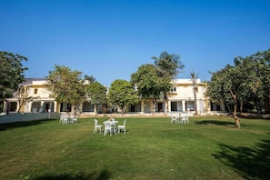 A building with a courtyard, outdoor seating, and trees. - Justa Alwarbagh Sariska (Alwar)