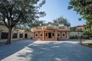 A courtyard with a building featuring arched windows and a central entrance. - Justa Alwarbagh Sariska (Alwar)