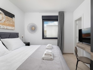 A hotel room with a bed, a TV, a desk, and a window with curtains. - Villa in Linardici With Swimming Pool (Krk)